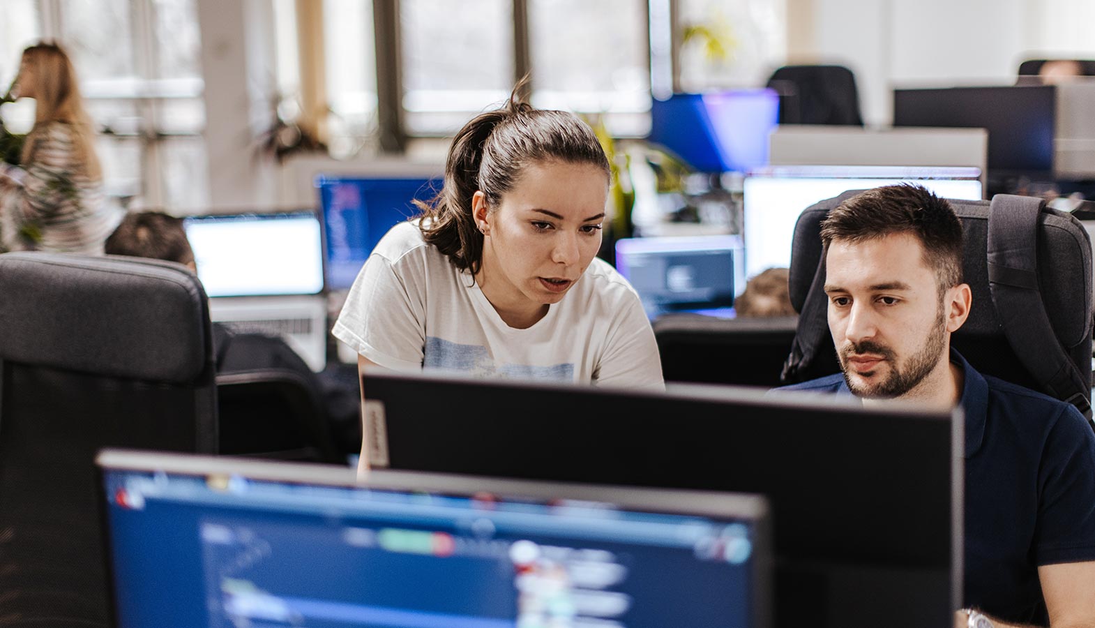 A customer support team is efficiently working at computer stations in a modern office, providing expert support for managed WordPress hosting solutions. They are equipped to assist with existing WordPress websites and ensure robust security and performance optimization for multiple client sites.