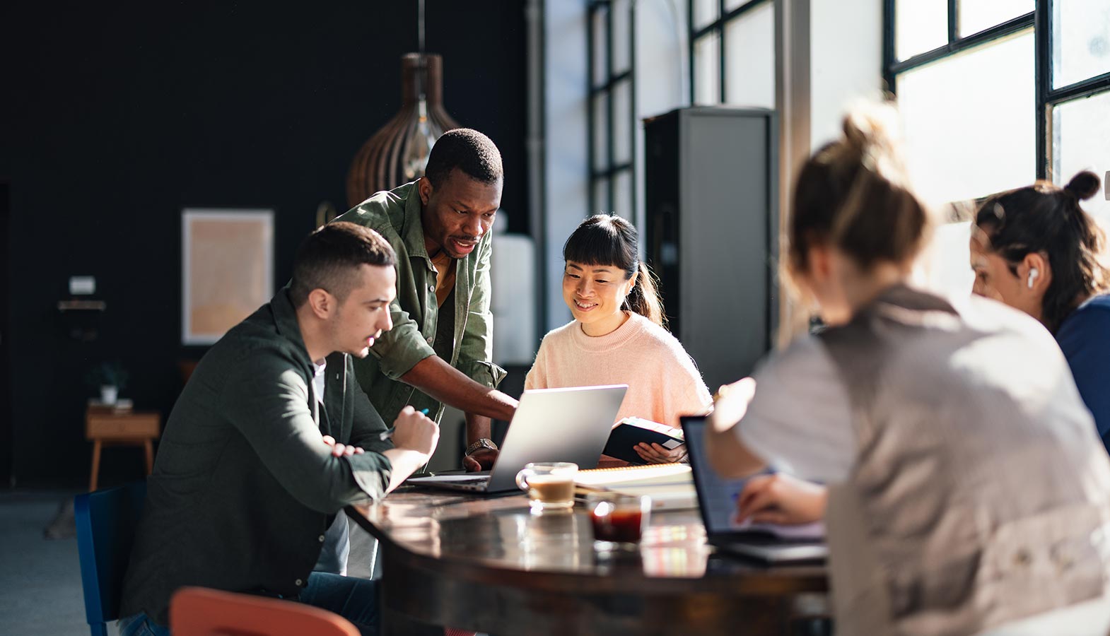 A professional design team is gathered around large display screens, reviewing website mockups and collaborating on digital marketing strategies. This scene showcases a web design company focused on creating visually appealing websites and custom web development solutions.