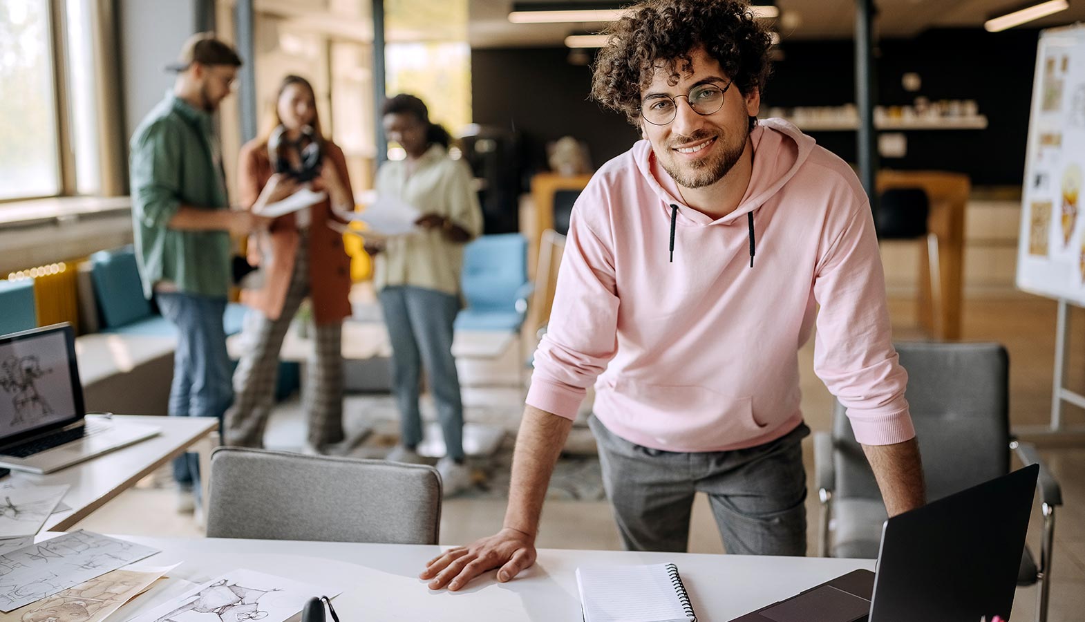 The image depicts a modern design studio workspace where a diverse group of professionals collaborates on creative projects, emphasizing teamwork in web design and development. The atmosphere is vibrant and dynamic, showcasing the innovative spirit of a top web design company in Canada.