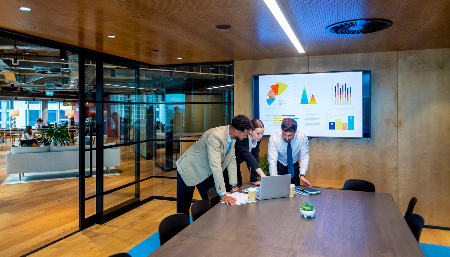 A group of business professionals is gathered around a large monitor in a modern Canadian office, reviewing various website designs. They are discussing elements such as user engagement and responsive web design, emphasizing the importance of choosing the right web design agency for their project.