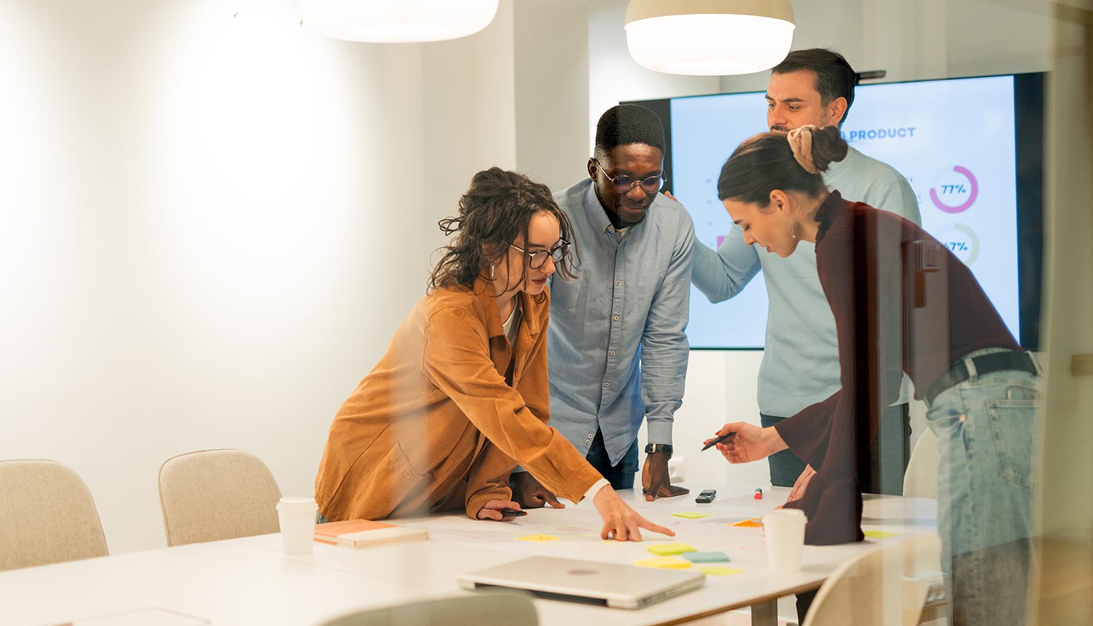 The image depicts a collaborative team meeting where designers and developers are actively discussing a web design project in a bright office space, showcasing their technical expertise and commitment to creating a visually stunning website that meets the client's business goals. The atmosphere reflects a successful partnership, emphasizing the importance of ongoing support and effective communication in the web design process.