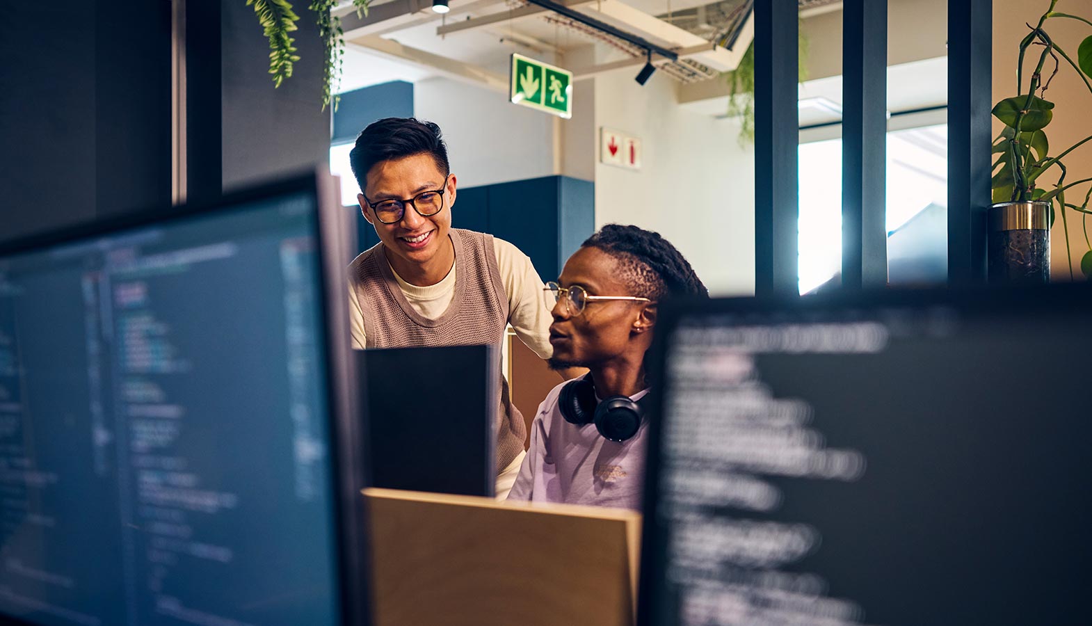 A professional team of web developers collaborates around multiple computer screens in a modern office, showcasing their expertise in web development and digital marketing. The atmosphere highlights teamwork and innovation as they work on custom software solutions and web design services to enhance their clients' digital presence.