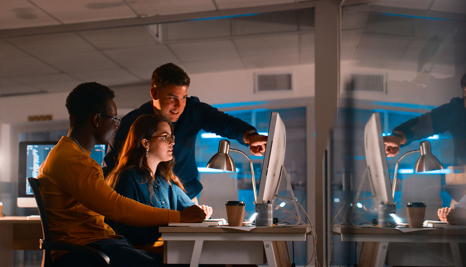 A professional team is collaborating at computers in a modern office environment, discussing strategies for search engine optimization and utilizing AI-powered tools to enhance their digital marketing efforts. The atmosphere is focused and dynamic, highlighting teamwork in the realm of SEO and content creation.