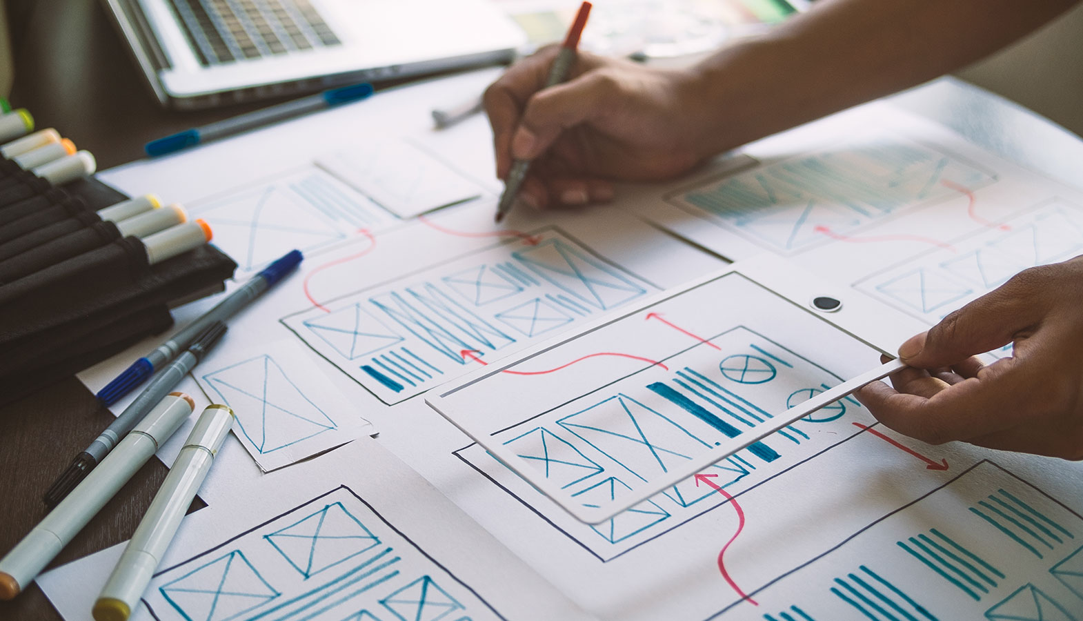 A design team is gathered around a table, actively reviewing wireframes and discussing user interactions for a web page. The atmosphere is collaborative as they focus on optimizing the page's responsiveness and improving input delays to enhance user satisfaction across both mobile and desktop devices.