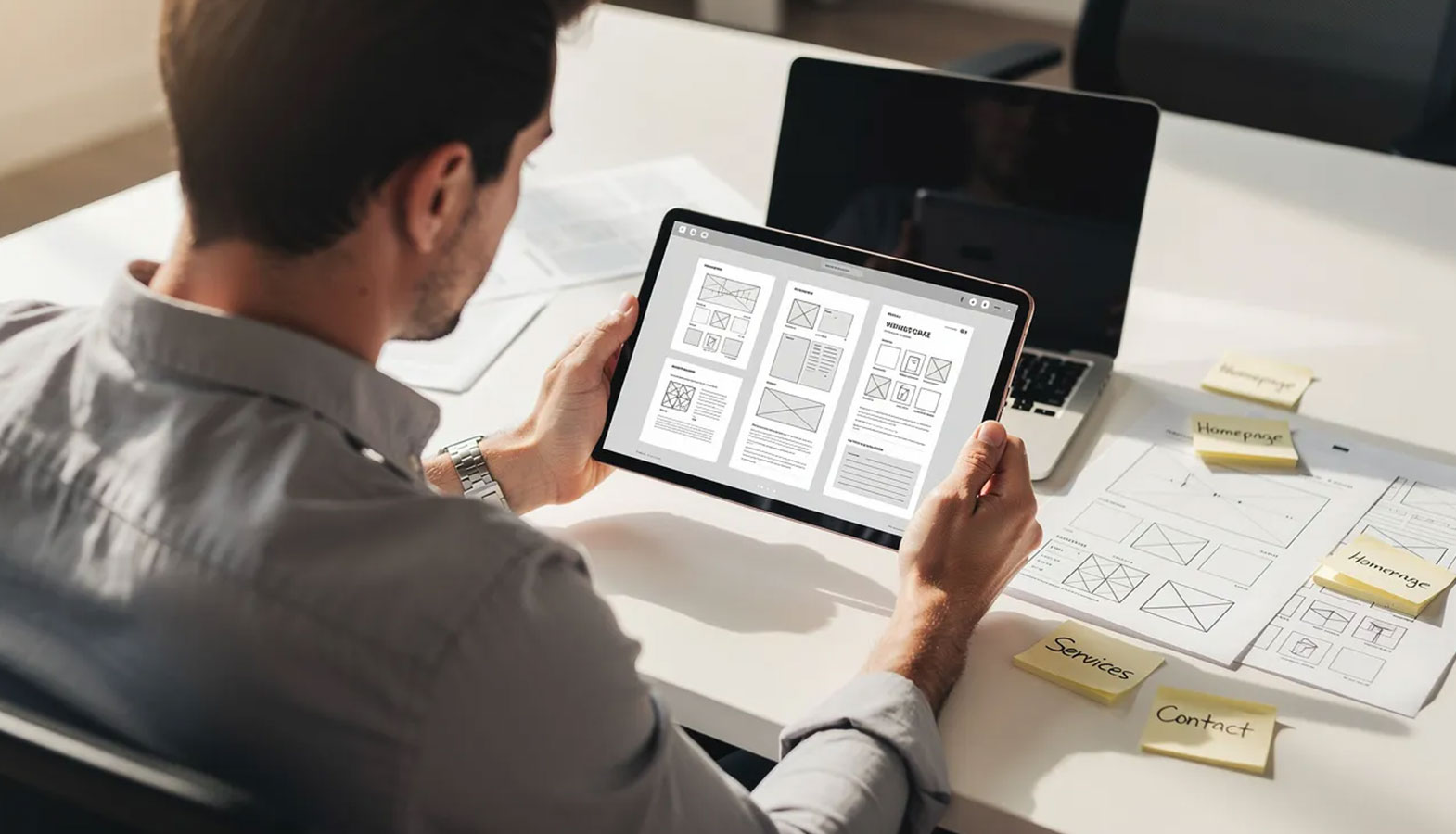 A business owner is intently reviewing website mockups on a tablet, indicating a focus on web design services for their business growth. The image captures the essence of a web design project, showcasing the importance of custom web design in enhancing digital presence for small businesses.