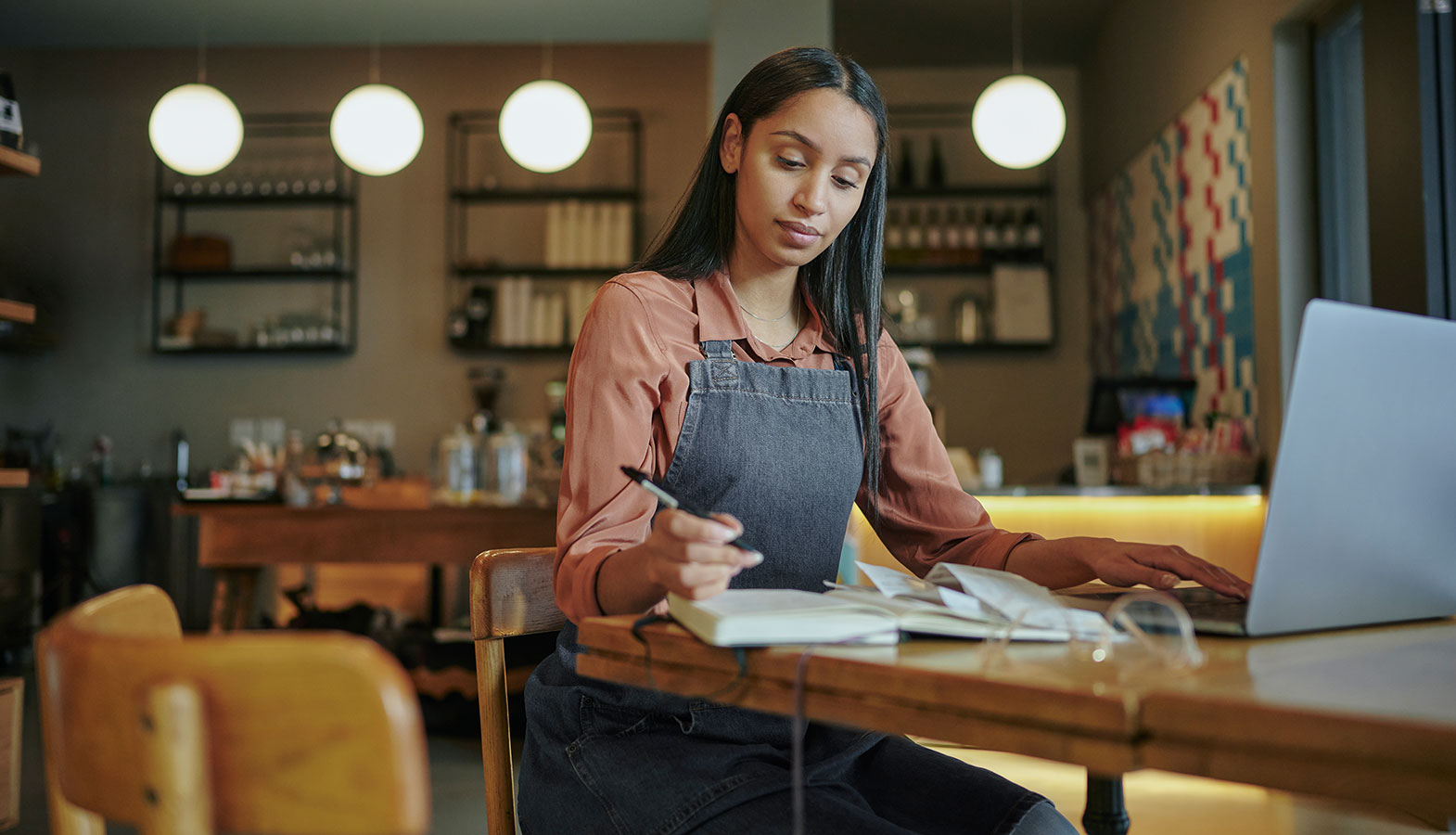 A small business owner is seated at a laptop inside a modern storefront, focused on their work, which likely involves web design and digital marketing strategies to enhance their business growth. The contemporary setting reflects a commitment to professional web design and innovative solutions for small businesses.