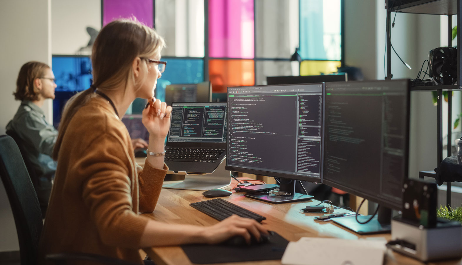 The image depicts a professional web developer focused on coding at a modern workstation equipped with multiple monitors, showcasing a dynamic workspace ideal for web development. This environment highlights the use of custom code and advanced development techniques, essential for creating and managing WordPress websites and plugins.